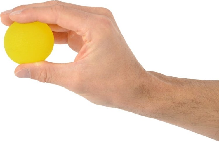 Ręka ściskająca piłkę Squeeze Ball w naturalnej pozycji — przykład ćwiczenia poprawiającego siłę palców i nadgarstka