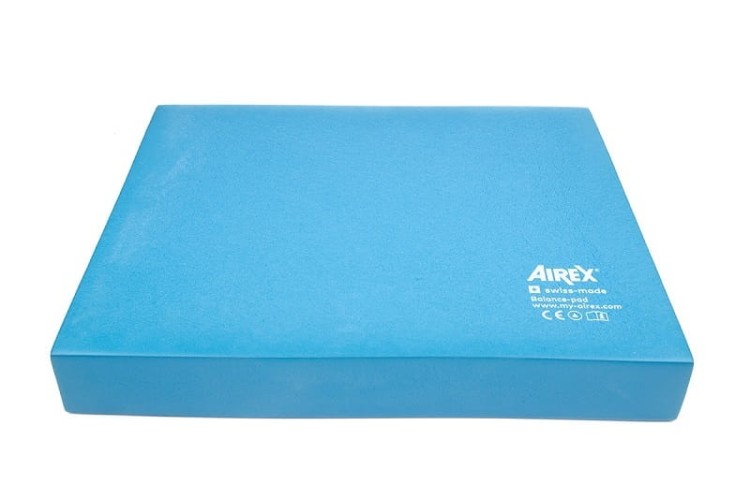 Airex Balance-pad używany przez osobę podczas ćwiczeń stojących w ośrodku rehabilitacyjnym, ukazujący pracę nad równowagą
