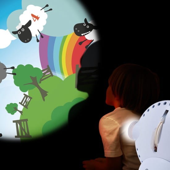 Projektor ustawiony przy oknie, wzory świetlne widoczne na wewnętrznej ścianie pokoju