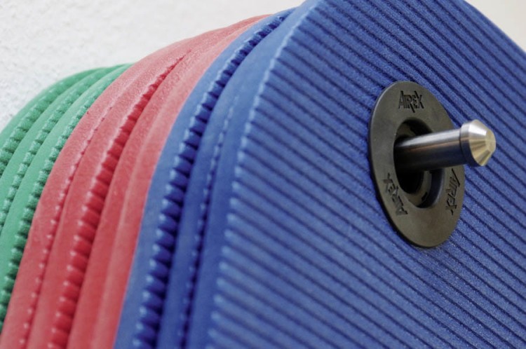 Wieszak Airex ze stali nierdzewnej zamontowany na ścianie; widoczna konstrukcja i oczka do zawieszania mat, wymiary 60 cm × 20 cm