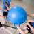 Piłka Ring Ball leżąca na sali gimnastycznej obok innych przyborów, pokazuje uniwersalne zastosowania i rozmiar 55 cm