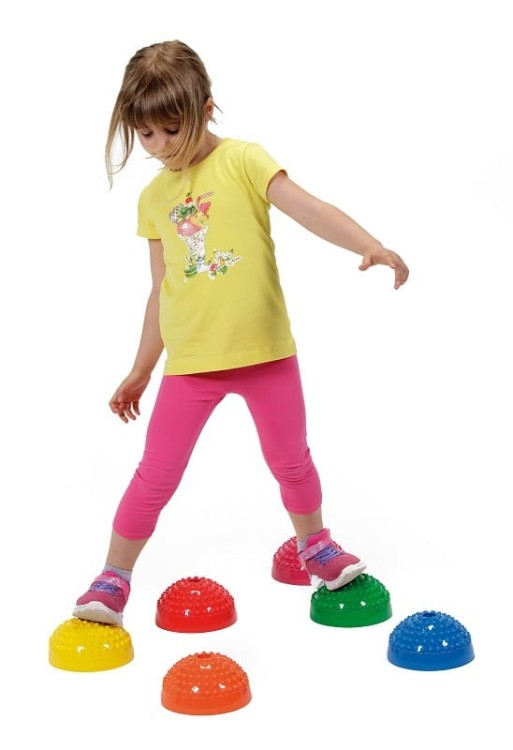 Dziecko ćwiczące na półkulach Gymnic Multiactiv Stones w kolorowym otoczeniu edukacyjnym