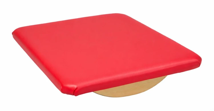 Kołyska równoważna mała ustawiona obok maty do ćwiczeń; kompaktowe wymiary 60 × 50 × 10 cm widoczne w aranżacji sali