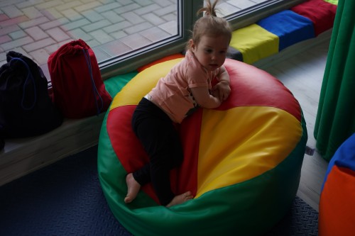 Ujęcie pufy sensorycznej 80 cm ustawionej na podłożu, pokazujące kształt, wysokość 30 cm i kolorystykę czerwono-żółto-niebieską