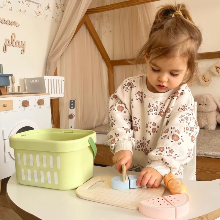 Elementy do krojenia z zestawu TOOKY TOY — deska, nożyk i drewniana ryba ukazane z bliska podczas zabawy