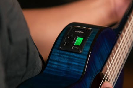 Guitarlele Ortega na tle naturalnego drewna z wyraźnym połyskliwym wykończeniem