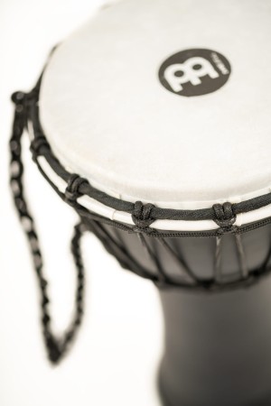 Czarne djembe umieszczone na drewnianym podłożu z widocznym bokiem instrumentu