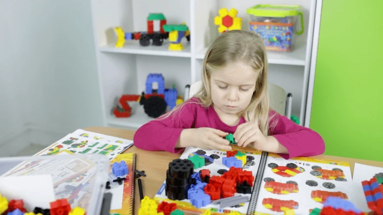 Dziecko pracujące z zestawem Morphun Junior przy stole w sali przedszkolnej, praca w grupie