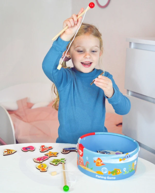 Ujęcie dziecka łowiącego rybkę w trakcie zabawy z grą zręcznościową TOOKY TOY — emocje i koncentracja
