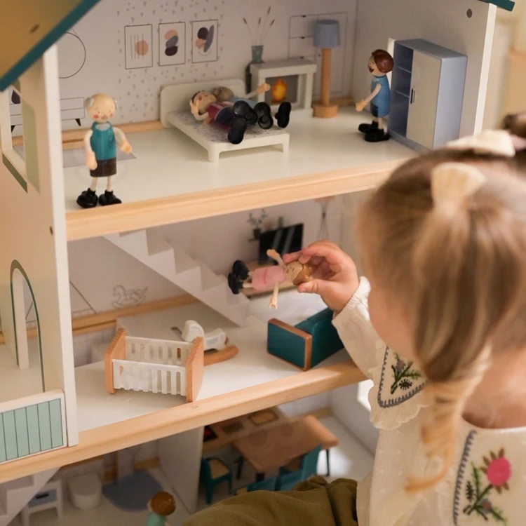 Mebelki we wnętrzu domku TOOKY TOY — stolik, krzesła i łóżeczko ułożone w przytulnym stylu dziecięcym