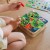 Dzieci bawiące się przy stole drewnianą grą Wyciągnij Robaczki 2w1 TOOKY TOY — scena użytkowania