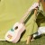 Zbliżenie na pudło rezonansowe drewnianego ukulele CLASSIC WORLD, widoczny różowy lakier i usłojenie drewna