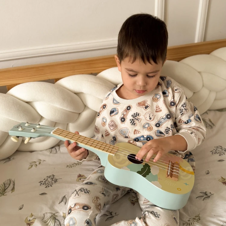 Zbliżenie na gryf ukulele dla dzieci — progi, struny i niebieskie zdobienie widoczne na szyjce