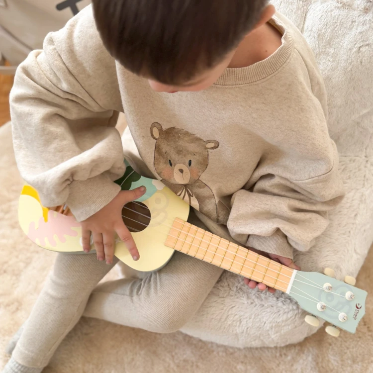 Detal mostka i mocowania strun ukulele — drewniana konstrukcja i precyzyjne wykończenie w niebieskim kolorze