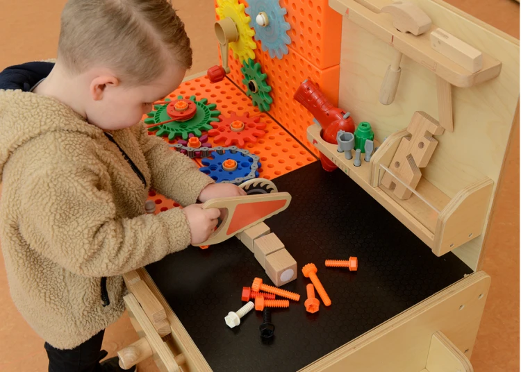 Widok z boku drewnianego warsztatu MASTERKIDZ — imadło, haczyki i półki na akcesoria