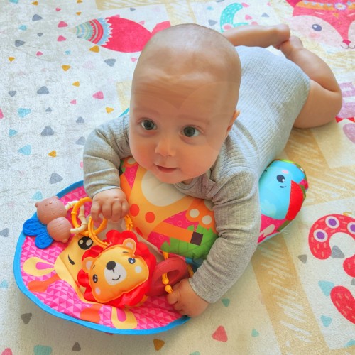 Zbliżenie na kolorową grzechotkę i gryzak przy macie edukacyjnej WOOPIE BABY — detal zabawy dla malucha