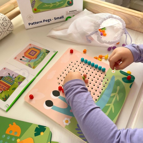 Zbliżenie na kolorowe pinezki i otwory układanki TOOKY TOY — widoczny detal kołków