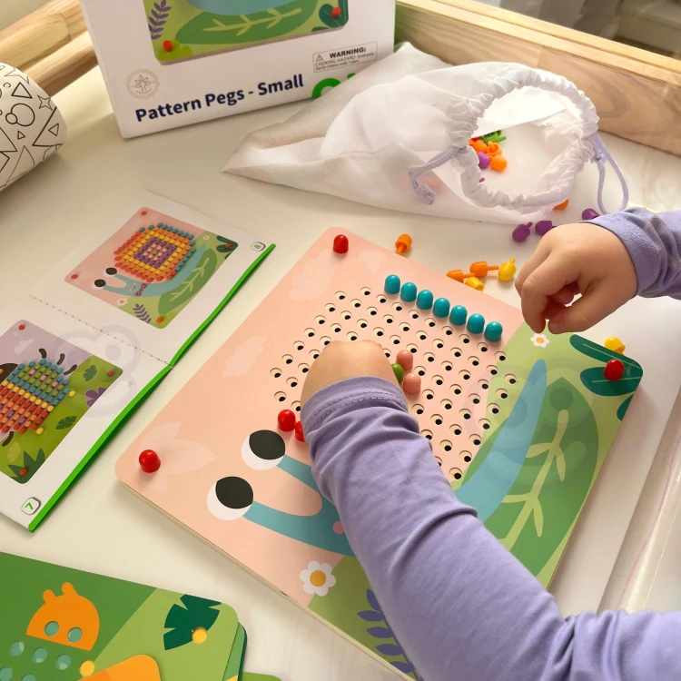 Zbliżenie na kolorowe pinezki i otwory układanki TOOKY TOY — widoczny detal kołków