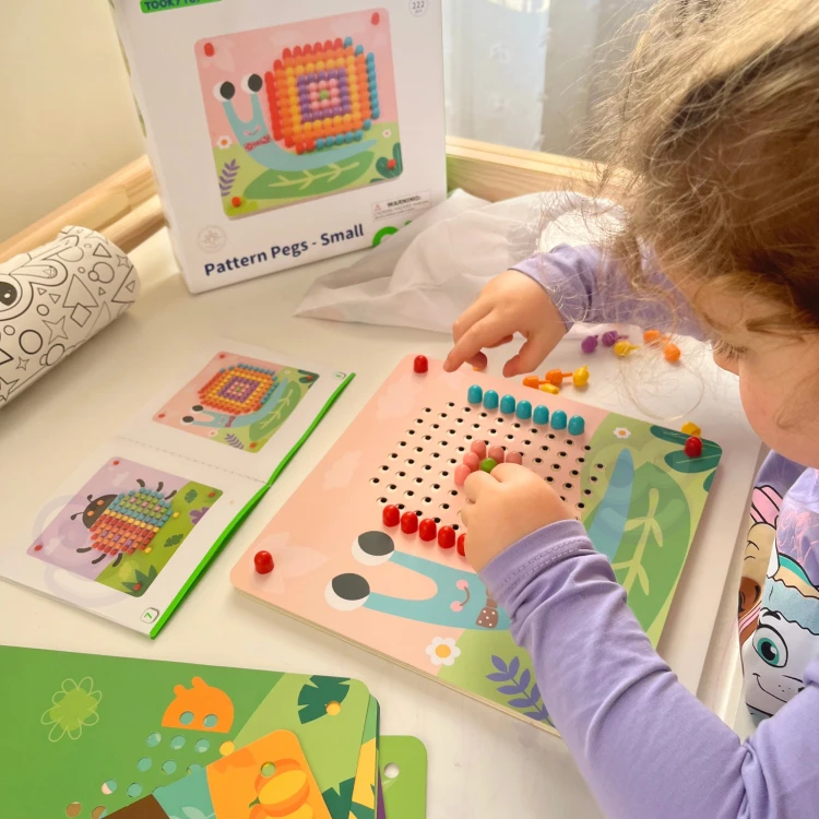 Dziecko bawiące się układanką z pinezkami TOOKY TOY — chwyt i umieszczanie kołków w otworach