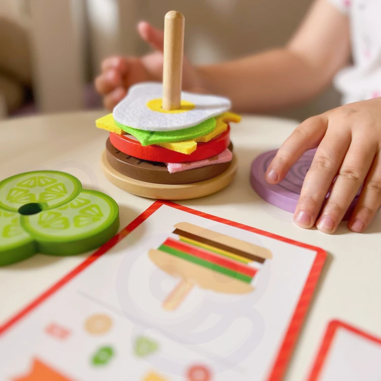 Widok rozłożonych 15 elementów układanki WOOPIE — składniki burgera ustawione obok siebie