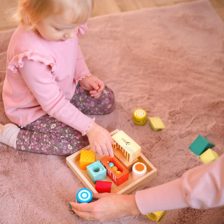 Kompozycja z elementami ułożonymi pionowo — klocki konstrukcyjne i sensoryczne w zestawie inspirowanym metodą Montessori
