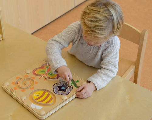 Zbliżenie magnetycznych elementów labiryntu — kolorowe owady i przesuwane koraliki na planszy
