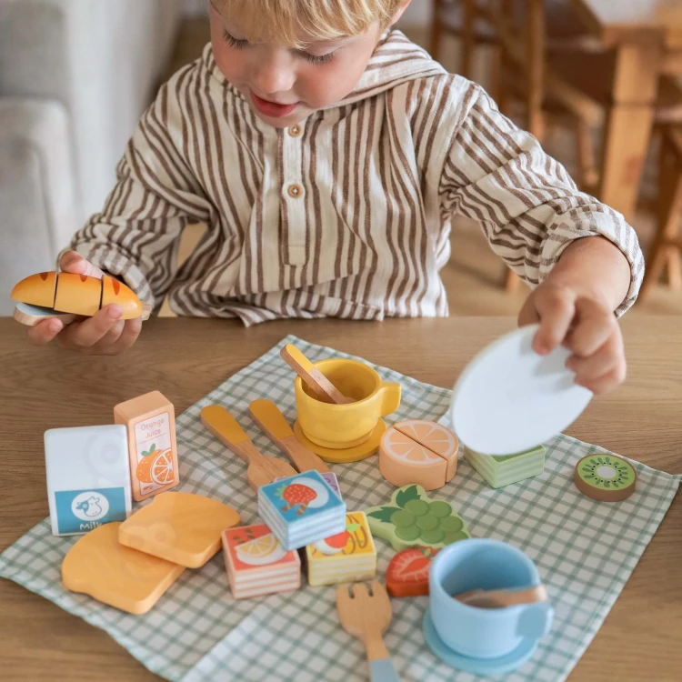 Widok z góry na elementy TOOKY TOY — talerzyki, kanapki i owoce do krojenia na rzepy ułożone na tacy