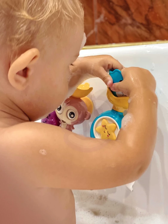 Porównanie rozmiaru: małpka trzymana w dłoni dziecka, detal kształtu i kolorów WOOPIE BABY