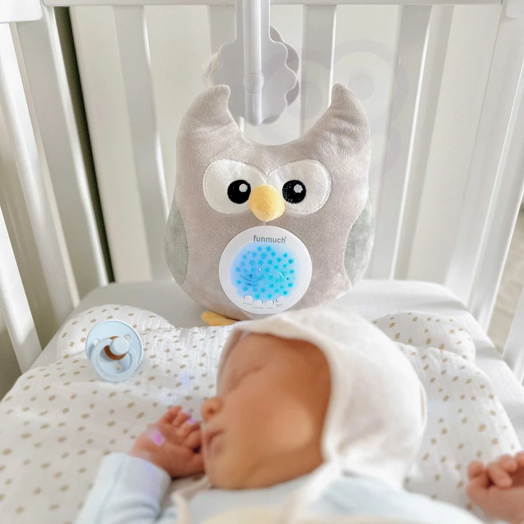 Sówka WOOPIE BABY ułożona na pościeli — pokaz rozmiaru i subtelnej miękkości maskotki