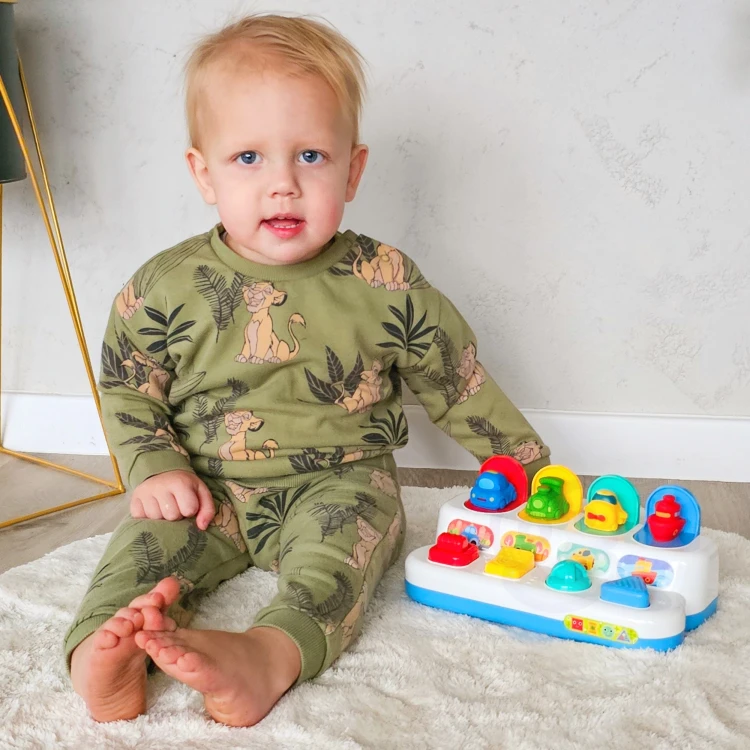 Ręka niemowlaka naciska przycisk WOOPIE BABY — pokaz działania zabawki edukacyjnej wyskakującej