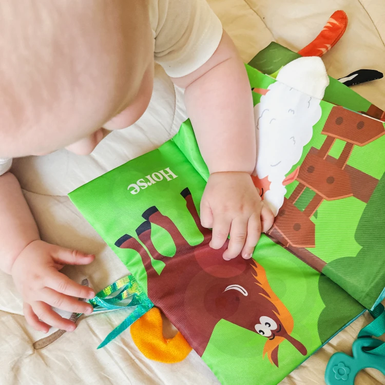 Książeczka w dłoni dziecka — pokaz rozmiaru i elastyczności materiału WOOPIE BABY podczas zabawy