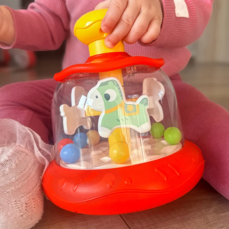 Karuzela WOOPIE BABY ustawiona na jasnym dywanie, widok z boku pokazujący profil i kolory elementów