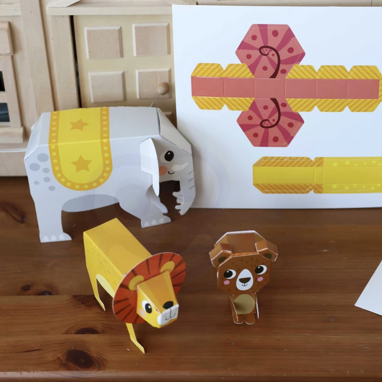 Ręce dziecka składające elementy origami 3D z zestawu WOOPIE — etap tworzenia jednego z dziesięciu zwierzaków