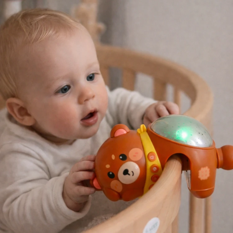 Lampka na stoliku nocnym — miś-projektor WOOPIE BABY ustawiony przy łóżku, delikatne rozproszone światło