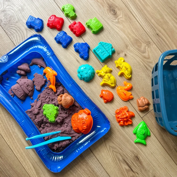 Koszyk z akcesoriami WOOPIE — widok z boku na foremki i opakowanie piasku kinetycznego