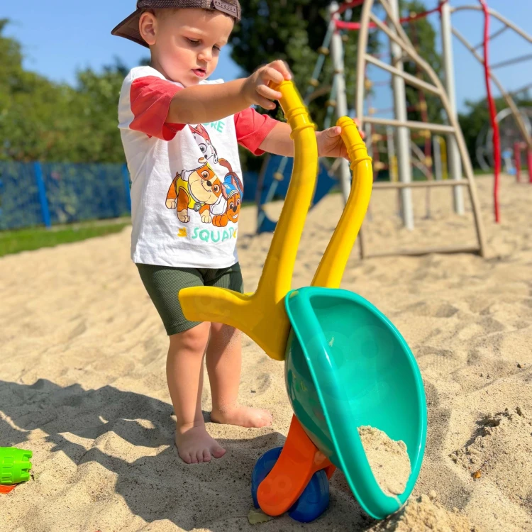 Taczka i akcesoria WOOPIE ustawione na trawie — pokaz zastosowania zestawu do piasku