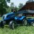 Traktor FALK New Holland w perspektywie 3/4 — kompletny widok pojazdu z przyczepą