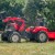 Perspektywa boczna traktora Case FALK z podpiętą przyczepką — widoczny pedał, osłona kół i ergonomiczne siedzenie