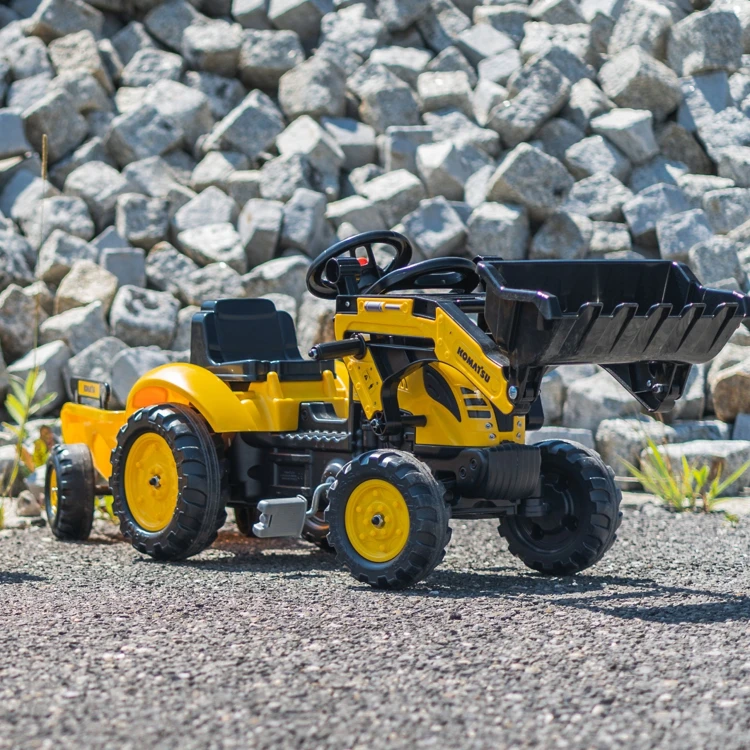 Widok boczny traktora z podniesioną łyżką — FALK Komatsu pokazujący mechanikę i przyczepę