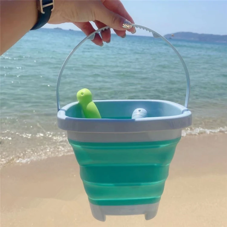 Łopatka i grabki WOOPIE trzymane w dłoni dziecka, ilustrują praktyczne zastosowanie zestawu na plaży