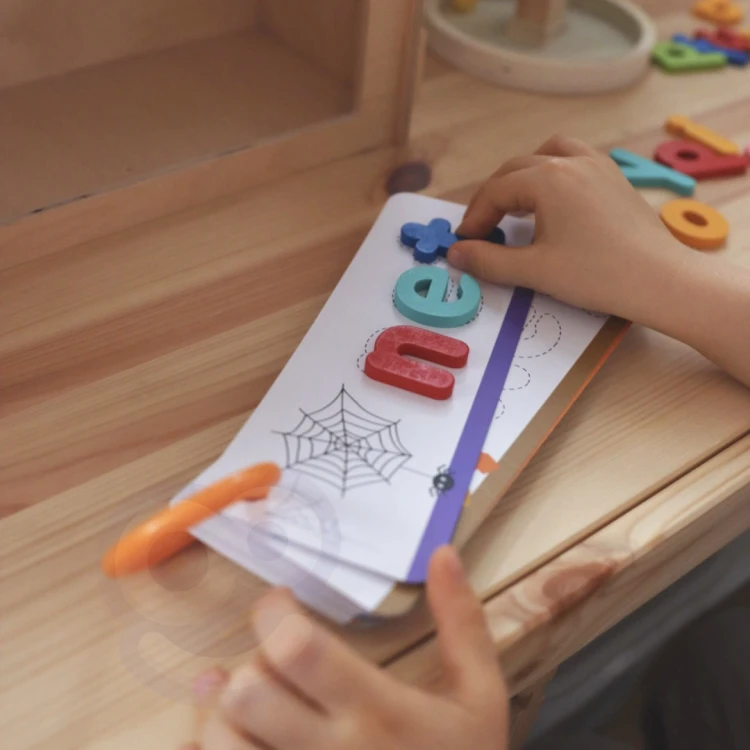 Dziecko układa literki z puzzli TOOKY TOY — scena zabawy edukacyjnej z drewnianymi elementami