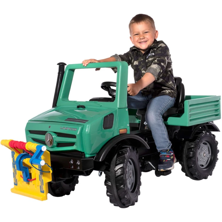 Dziecko prowadzące ciężarówkę na pedały RollyUnimog w ogrodzie, zabawa i ruch na świeżym powietrzu