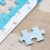Dziecko układa Puzzle Mapa Świata 50 — ręce dopasowują element w centralnej części planszy