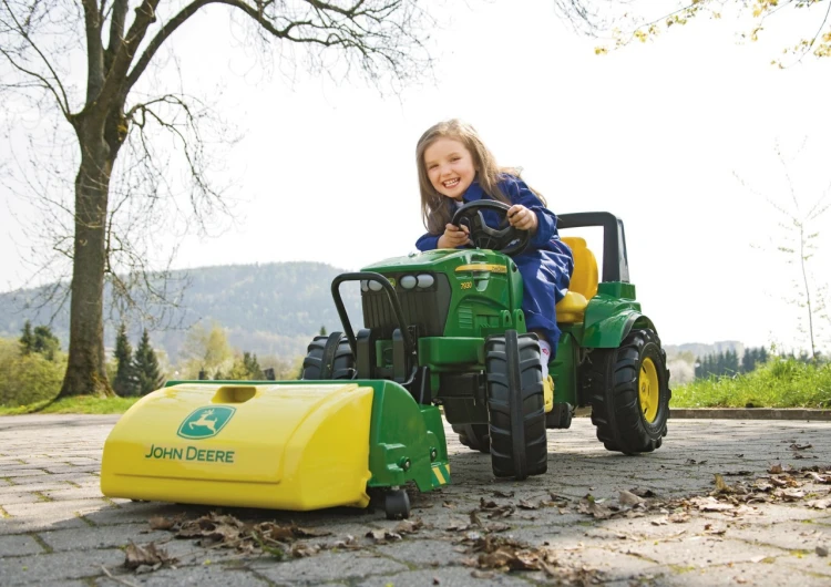Zamiatarka Rolly Toys — widok boczny ukazujący koła, mechanizm szczotki i podwozie z logo John Deere