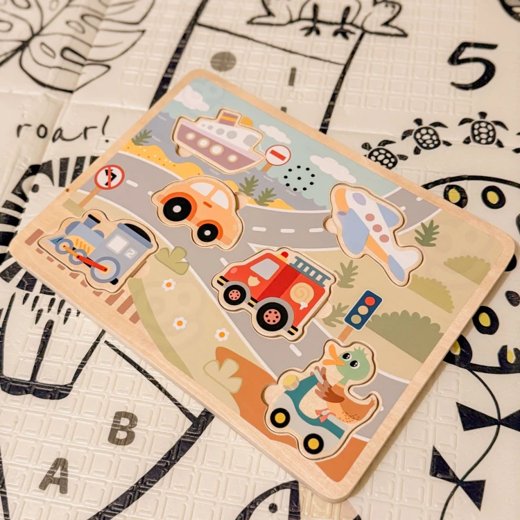 Kilka pojazdów ustawionych obok planszy — komplet Drewniane Interaktywne Puzzle Pojazdy TOOKY TOY w całości