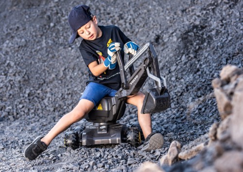 Boczny kadr rollyDigger Rolly Toys — widoczna obrotowa łyżka koparki i profil jeździka, detale wykończenia