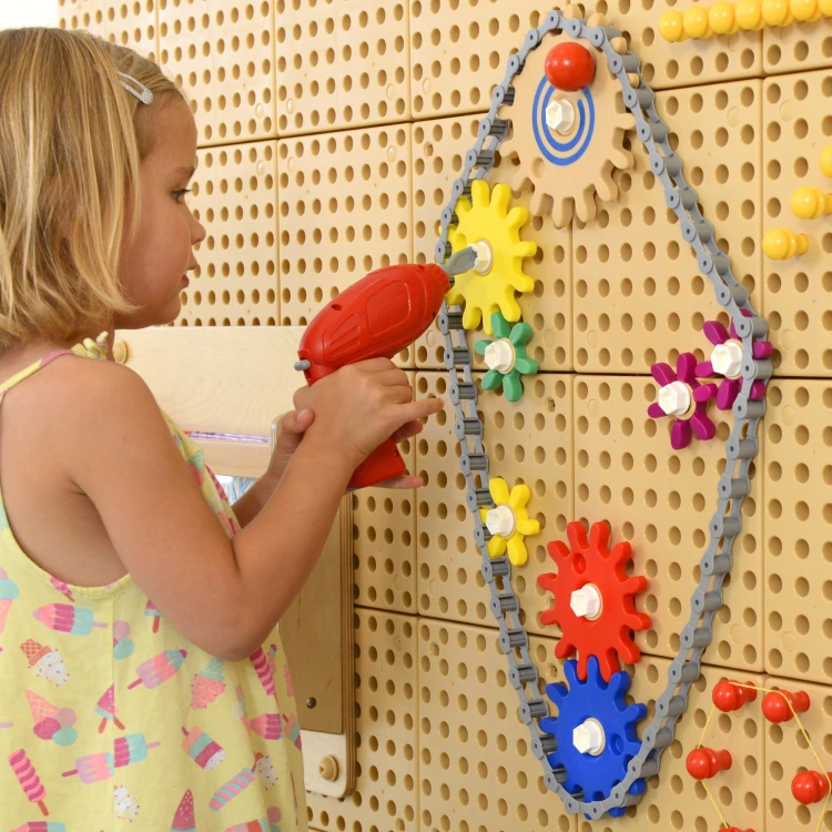 Interakcja z elementami — ręka kręci koło zębate na tablicy MASTERKIDZ, widoczne połączenia i osie