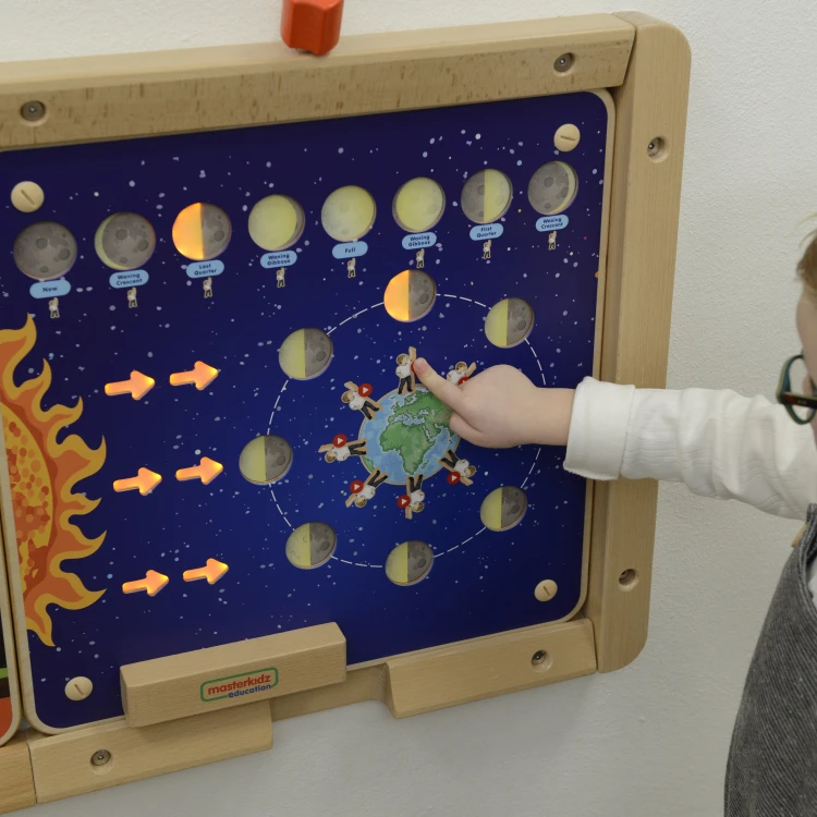 Dziecko przesuwa elementy tablicy Montessori, ćwicząc rozpoznawanie faz Księżyca z pomocą MASTERKIDZ