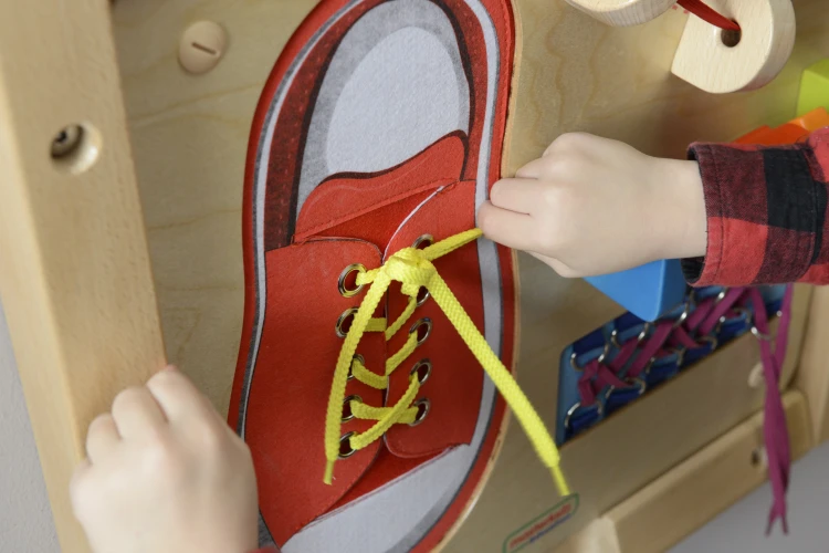 Ręka dziecka ćwiczy wiązanie na tablicy MASTERKIDZ — praktyczne zastosowanie do rozwijania zręczności manualnej