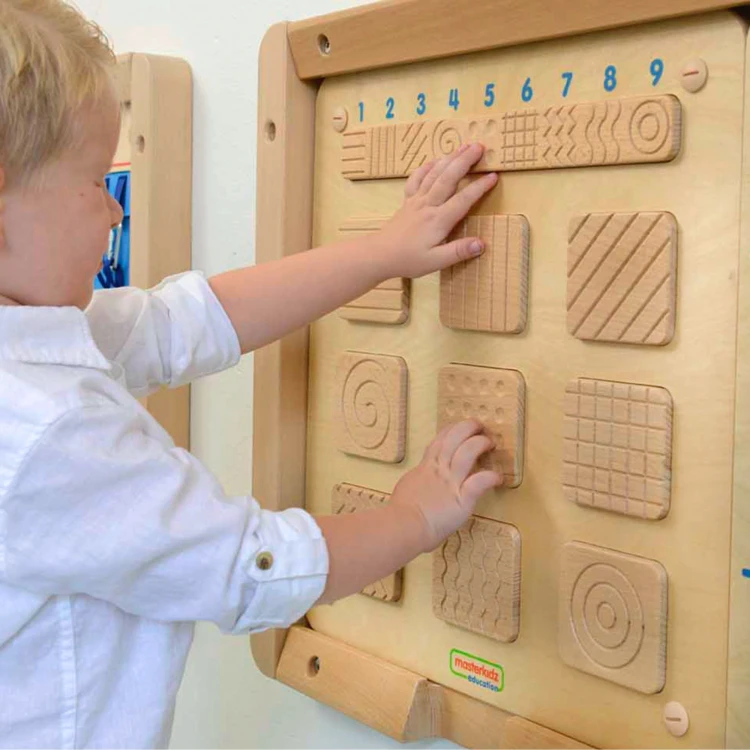 Dziecko dotyka struktur na sensorycznej tablicy MASTERKIDZ — detal dłoni i kontrast faktur powierzchni